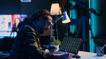 Self employed broker investor in home office checking stock exchange profit, calculating using pen and paper. Freelancer in apartment looking at market shares growth, writing on notepad, camera A photo