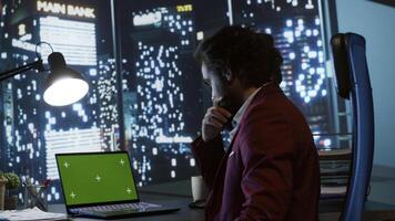 Legal investor works with greenscreen on pc at workstation, examining isolated chromakey display from panoramic view office. Chief executive director working at night with copyspace template. photo
