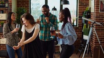 Diverse mix of guests at home party sharing laughter and dance moves in living room, dolly in shot. Friends dancing on disco beats during weekend hangout, shaking their shoulders photo