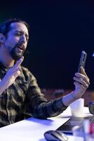 Side view of male university student utilizing his mobile device to conduct a call conversation. Youthful man using hand gestures in virtual meeting with his colleagues through his smartphone. photo