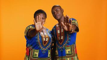 Serious african american couple show stop sign on camera, raising palm and expressing their refusal. Man and woman doing rejection gesture and being displeased about something, disagreement. photo