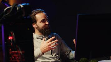 Streamer talking to viewers live, presenting next game he will play, providing info and reviewing. Pro gamer broadcasting from dark apartment, greeting fans watching him on online channel photo
