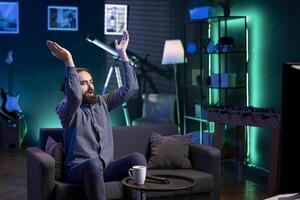 Jolly man clapping hands after favorite team wins while watching live sports event broadcasted on TV. Happy supporter applauding own club, enjoying football competition victory photo