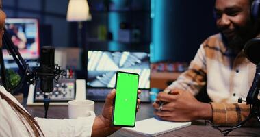 Isolated screen cellphone in front of show presenter recording podcast, enjoying cup of coffee and nice conversation with guest. Chroma key phone in studio used for live broadcast with woman photo