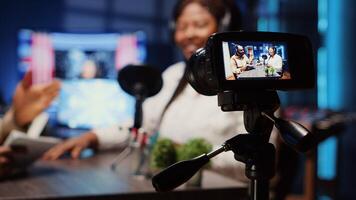 Focus on professional camera recording man in blurry background using high tech microphones to interview guest, ensuring optimum and sound quality for audience watching at home, close up photo