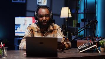 Portrait of BIPOC content creator broadcasting live on streaming platform from vibrant studio using professional tools producing high quality audio. Man creating engaging social media content photo