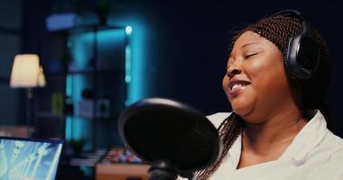 Zoom in on african american woman streaming podcast using vlogging camera during live political debate on vlog channel. Internet show presenter in dimly lit studio, close up photo