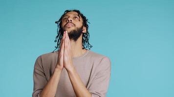 Pious Middle Eastern man praying to his god, asking for forgiveness, feeling desperate. Spiritual BIPOC man doing worship hand gesturing, confessing, begging for pardon, studio background, camera B photo