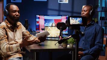 Man on podcast using professional equipment while talking with guest during marathon live broadcast for good humanitarian cause, gathering donations from viewers, filming with camera, panning shot photo