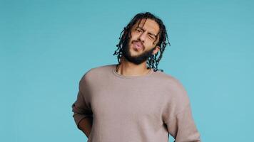 Hurt Middle Eastern man screaming from pain, suffering from back injury, having health problems. Injured BIPOC person feeling uncomfortable ache, yelling, studio background, camera B photo