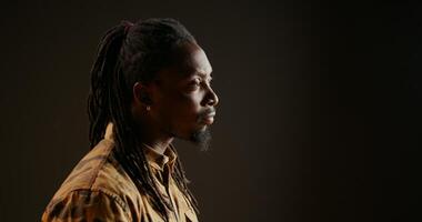 African american person being surprised seeing something in studio, being amazed and admiring view over black background. Male model looking around and feeling shocked, saying wow. photo