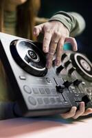 Girl filming mixing tutorial in home studio, showing examples of sampling on sound controller to viewers, close up shot. DJ showing high tech musical gear to interested fans photo