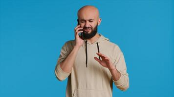Middle eastern guy chatting with friends on phone call, answering smartphone while standing over blue background. Modern man discussing something on a remote network. Camera 1. photo