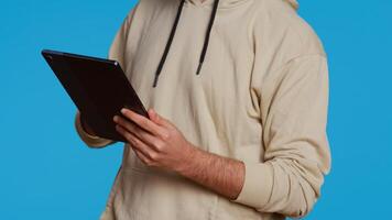 Arab guy using tablet to scroll on online websites, looking for something on the internet and using social media apps. Modern person working with touchscreen device in studio. Camera 2. photo