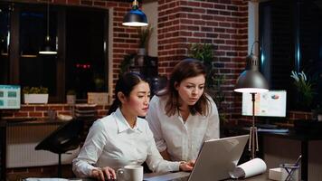 Asian employee brainstorming with coworker to compose email at computer desk, finalizing deal with business partners. Businesswoman and colleague closing agreement with associates, camera A photo