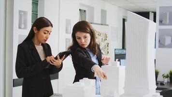 Architects translating 3d building measurements on tablet, working in real estate agency office where architectural vision takes shape. Team of engineers calculating draft lines and elements. photo