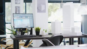 Designing office has empty desk with computer operating cad, production layouts and blueprints on the design table. Architectural work environment fitted with latest modeling appliances. photo