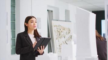 In property management office, contractor uses tablet to evaluate and estimate variables as they work with 3D printed architectural prototype. Engineer working to design urban area with housing. photo