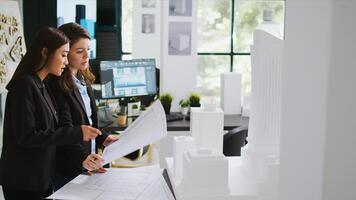 Architects team studying 3d printed building model in office, looking at scale and outline to reveal floor plan measurements. Creative agency employees working with architectural blueprints. photo