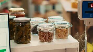 Cereals and grains in reusable jars placed on checkout counter at local eco supermarket, low carbon footprint locally grown merchandise. Organic fresh chemicals free products in store. Close up. photo