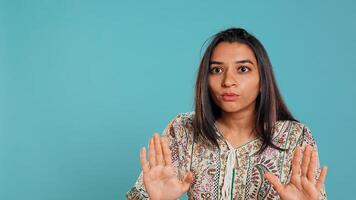 Stern indian woman doing stop hand gesture sign, complaining. Authoritative person doing firm halt sign gesturing, wishing to end concept, isolated over studio background, camera B photo