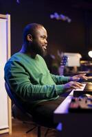 Artist playing piano electronic keyboard and recording new sounds, producing new midi controller notes in his home studio. Audio producer working with digital audio workstation software. photo