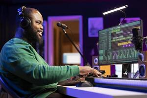Sound engineer working with mixing console and synthesizer to edit his audio files, using digital software interface for mix and master session in post production. Musician launching an album. photo