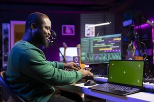 Confident musician producing new tunes next to a greenscreen display, working on mix and master in post production. Music producer creating sounds to add effects on old recordings. photo