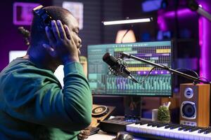 Creative artist songwriter recording his voice and lyrics in home studio, working on creating new soundtracks with microphone and stereo gear. Musician performing a tune, edit with mixing console. photo