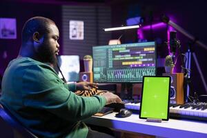 Audio technician composing new tracks with digital mix master software, having a tablet with isolated copyspace on desk. Professional engineer editing music in post production. photo