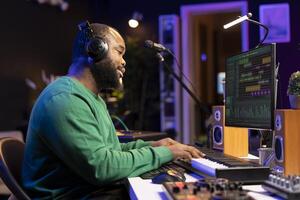 Young audio technician playing around with piano tunes on other songs, mixing and mastering to compose a new soundtrack. Skilled producer works in home studio to create music. photo
