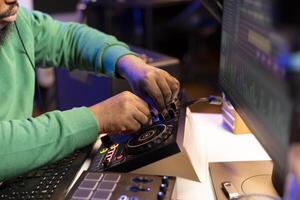 Audio engineer producing new music on mixing console in home studio, working with sound effects and pre amp knobs. Skilled producer creating songs and adjusting volume levels. Close up. photo
