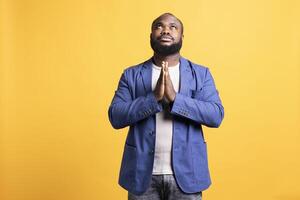 piadoso africano americano hombre Orando a su dios, preguntando para perdón. espiritual bipoc hombre haciendo Adoración mano gesticulando, confesando, mendicidad para indulto, aislado terminado estudio antecedentes foto