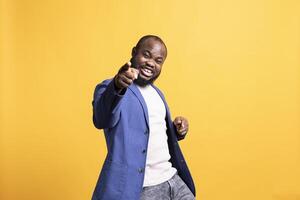 Portrait of flashy motivational speaker pointing finger to audience with determination, isolated over studio background. Expressive vigorous BIPOC lecturer showing intense emotion photo