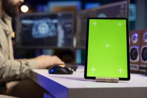 IT expert scripting artificial intelligence on computer with green screen tablet on desk next to it. Programmer working on coding AI on desktop PC with chroma key device near photo