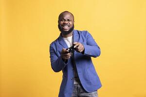 Upbeat person playing intense gaming console game, having fun, isolated over studio background. Joyous man pleased after being victorious in videogame, defeating all enemies using gamepad photo