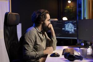 Programmer updating artificial intelligence deep learning algorithm, writing binary code scripts. IT specialist in apartment office uses programming to upgrade AI, waiting for software to load photo
