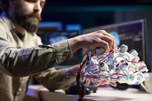 Computer scientist installing electrodes wires on EEG headset to communicate with artificial intelligence entity. Close up shot of high tech gear used by IT expert to talk with AI robot photo