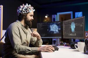 Man using EEG headset to communicate with artificial intelligence on computer in binary code. Programmer sending brainwave signals to AI entity on PC using high tech device photo