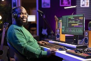 Portrait of sound engineer working on producing music in home studio, adjusting volume levels by twisting pre amp knobs at workstation. Producer creating new tracks on DAW software. photo