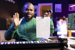 Talented composer explaining musical sheet notes during an online master class recorded with smartphone in home studio. Artist musician teaching people how to read and sing the accords on piano. photo