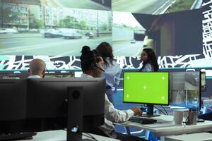 Indian employee operates on mockup display next to CCTV real time , monitoring couriers activity through urban traffic via public surveillance system. Dispatcher in control center. photo