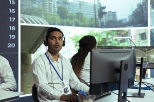 Indian employee following real time traffic activity on CCTV system cameras, registering any illegal driver behavior in the city. Male operator monitoring cars, plate recognition. photo