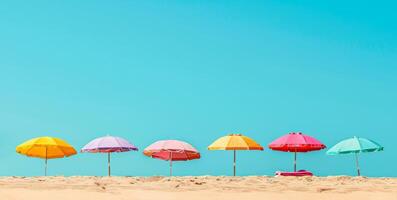 Colorful beach umbrellas lined up on a sandy beach with clear blue skies and bright sunlight. Concept of beach resort, summer vacation, sun protection, and leisure. Banner. Copy space photo