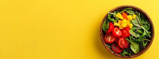 Wooden bowl of fresh salad with tomatoes spinach and bell peppers on yellow background. Vegetables, healthy eating, food nutrition, diet concept. Banner. Copy space. Foods for healthy heart photo