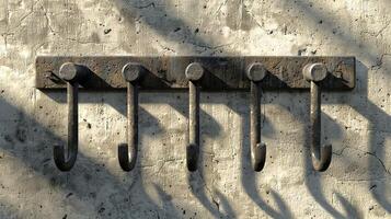 Antique metal hooks on a rustic concrete wall. Vintage hardware for hanging items. Concept of home decor, historic design, wall-mounted utility tools, rustic aesthetics photo