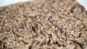 A close up of a piece of bread with a lot of seeds on it. The bread is brown and has a lot of texture. video