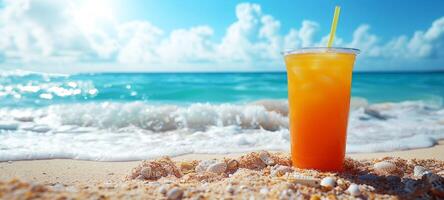 Refreshing orange drink in a clear plastic cup on a sandy beach. Beverage by the sea with shimmering sunlight. Concept of summer refreshment, beach relaxation, tropical cocktails. Space for text photo