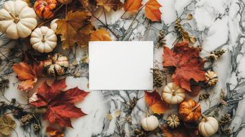 Autumn leaves and pumpkins on marble backdrop. Blank paper sheet for text in center. Thanksgiving mockup with copy space. Concept of fall, holiday card template, Thanksgiving design, harvest festival photo