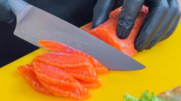 Close up of chef slicing fresh salmon on a yellow cutting board for sushi preparation, conceptually related to culinary arts and healthy eating photo